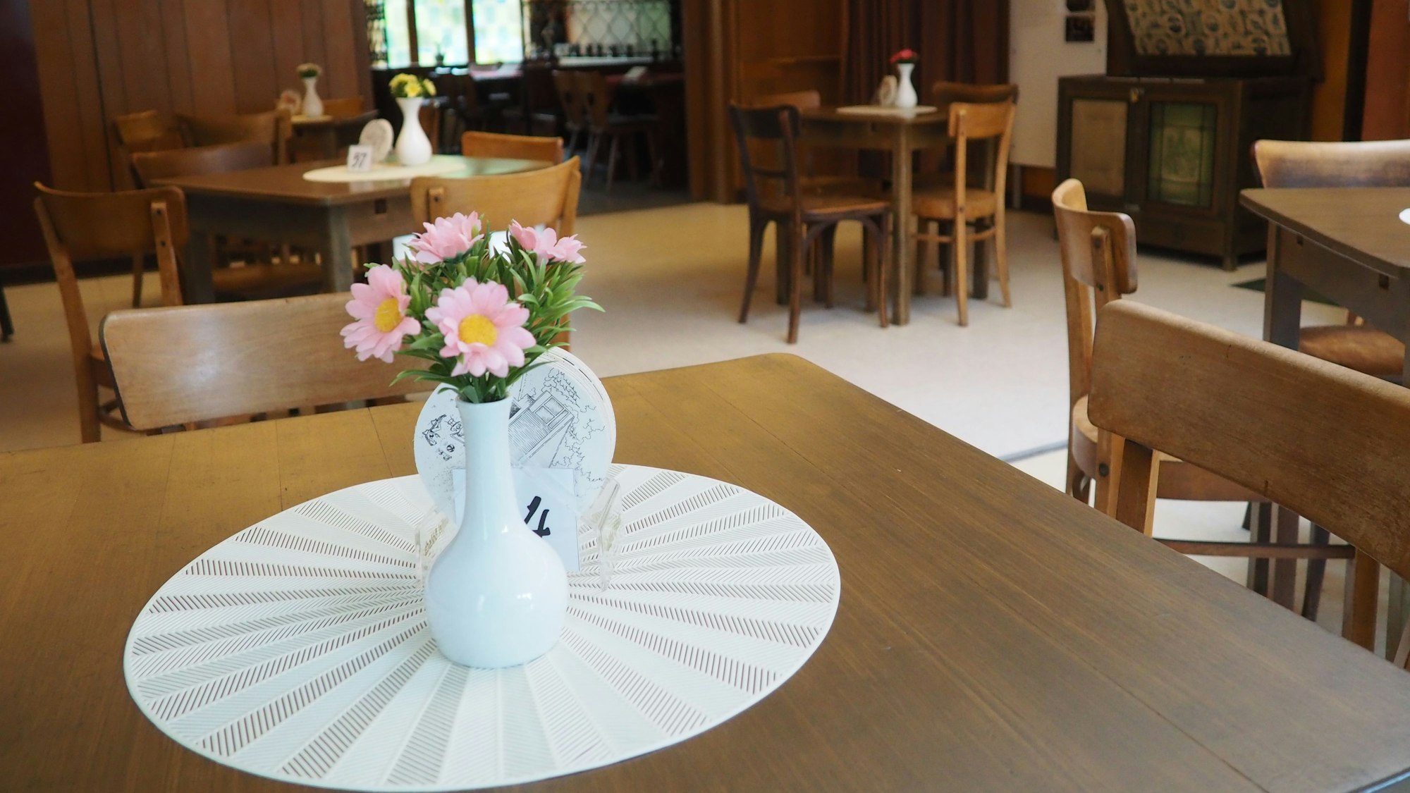 Ganz im Stil der 1970er-Jahre ist ein Tisch in der Gaststätte Watteler im Freilichtmuseum Kommern mit einem Häkeldeckchen, einer kleinen, weißen Vase und ein paar rosa-gelben Blumen dekoriert.