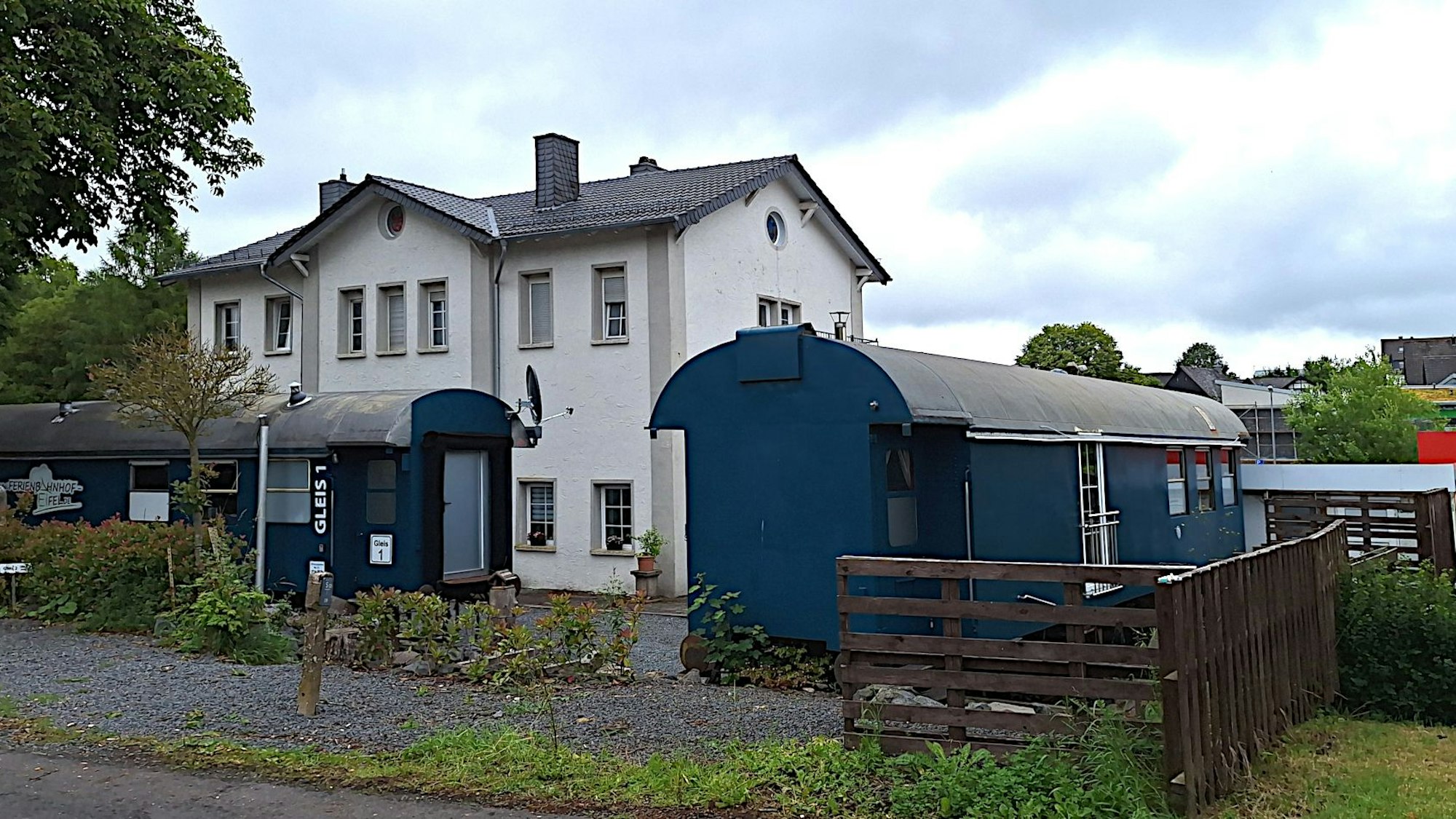 Am Gebäude des alten Bahnhofs von Schmidtheim stehen zwei Bahnwaggons, die heute als Ferienwohnungen genutzt werden.