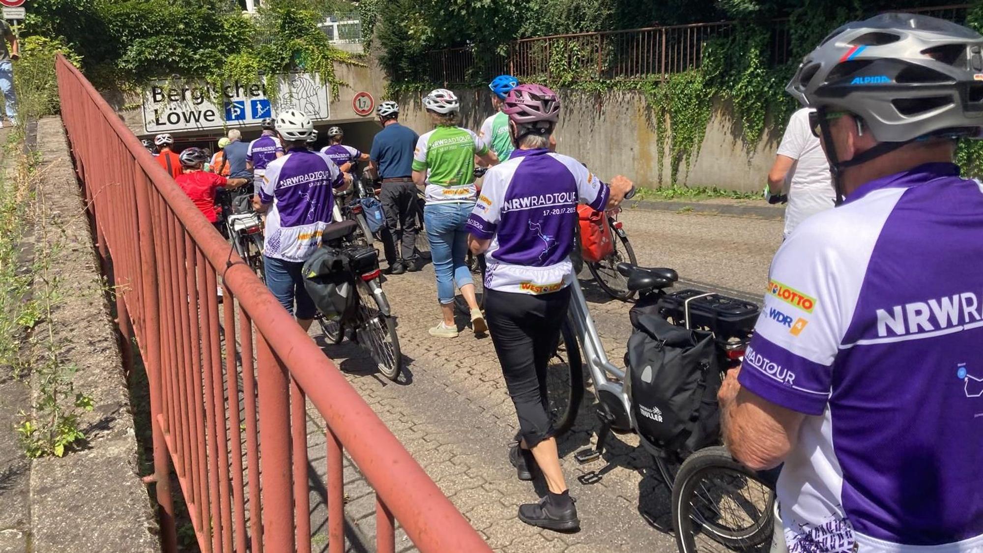 Mehrere Radfahrer sind laufend neben ihrem Rad zu sehen.