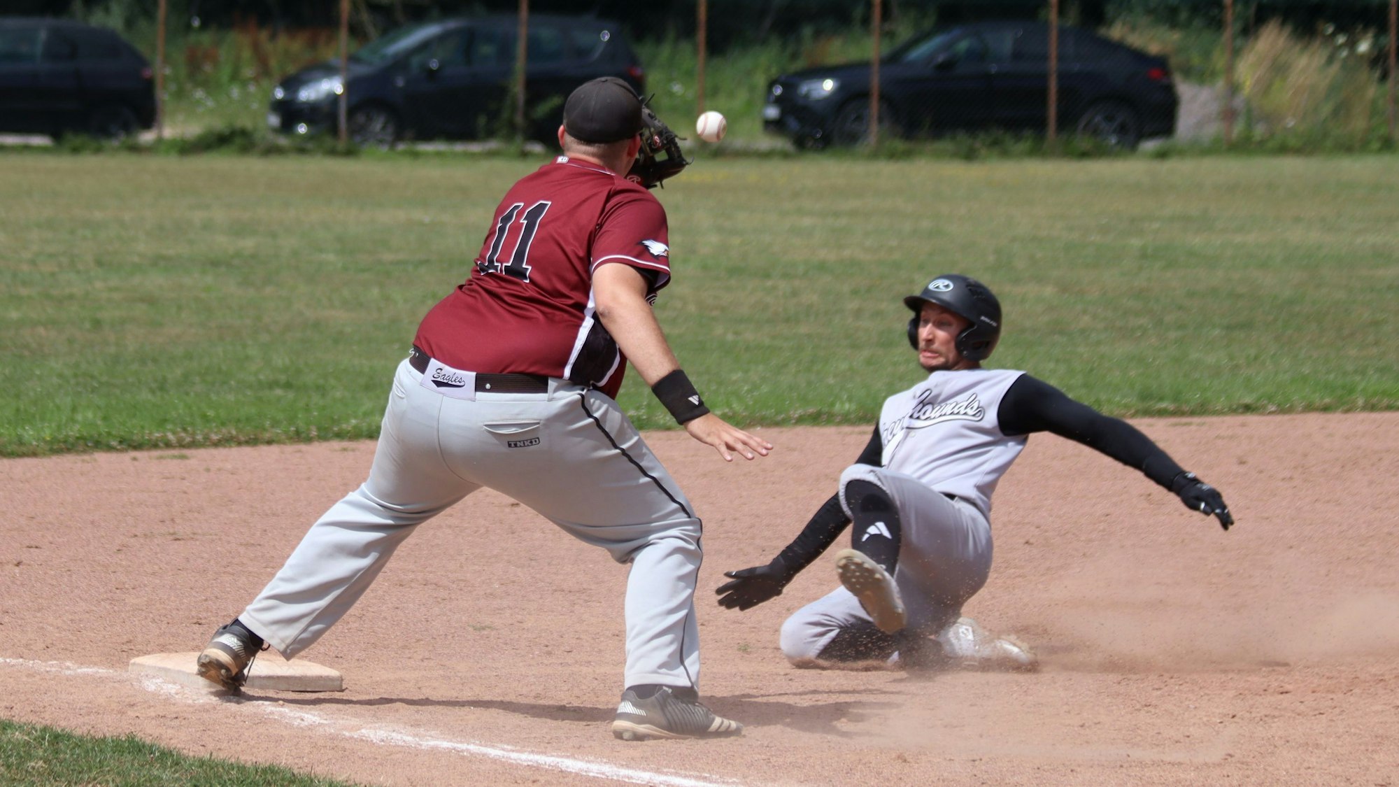 Ein Zülpicher Catcher versucht einen Ball zu fangen, während ein Gegenspieler aus Aachen sich Richtung Base wirft.