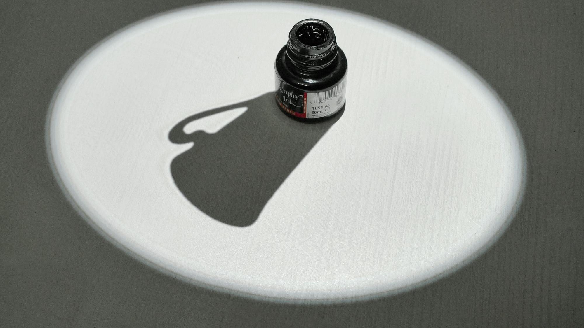 Ein Tintenfass wirft den Schatten einer Kaffeetasse.