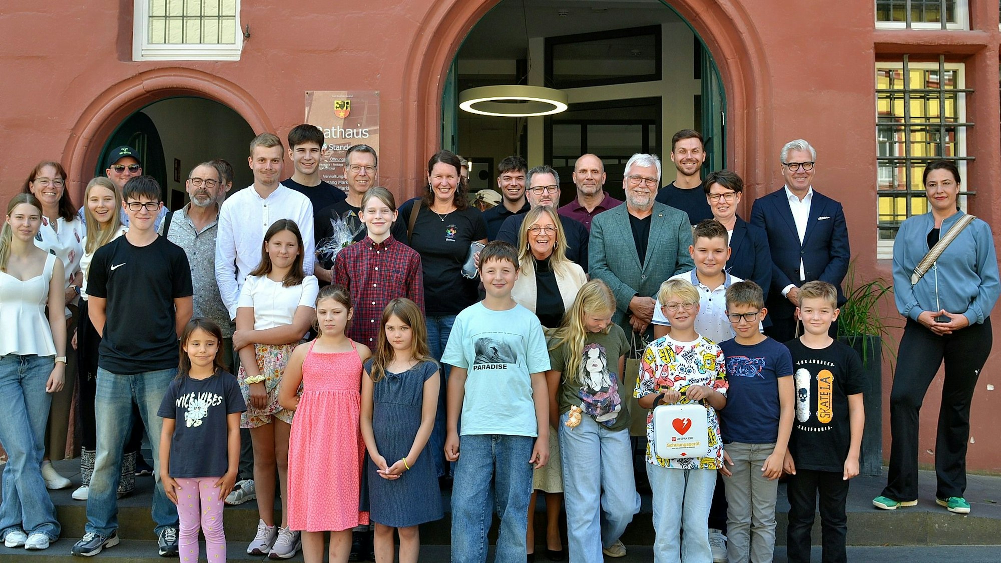 Eine Gruppe Kinder und Erwachsene steht vor einem Gebäude.