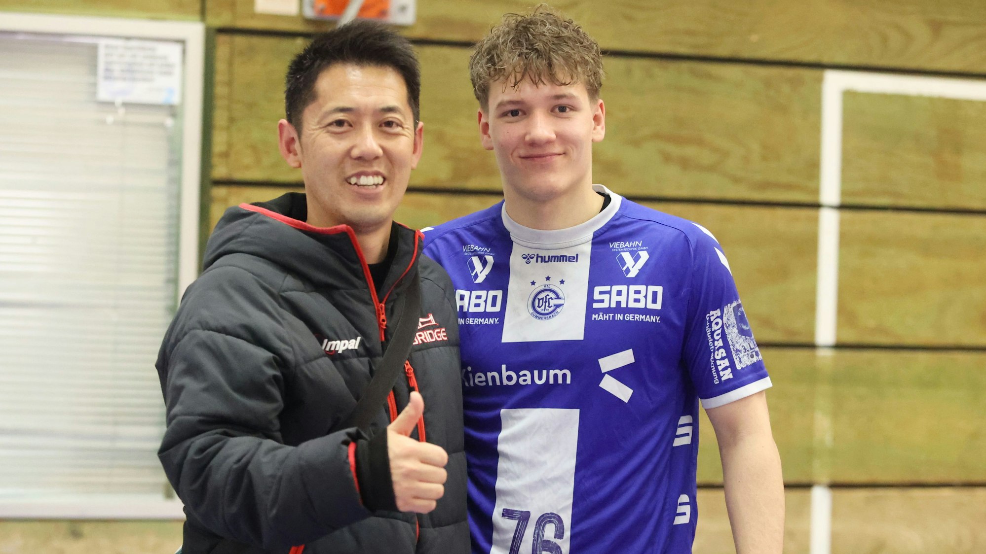 Ein Handballspieler und ein Trainer stehen zusammen.