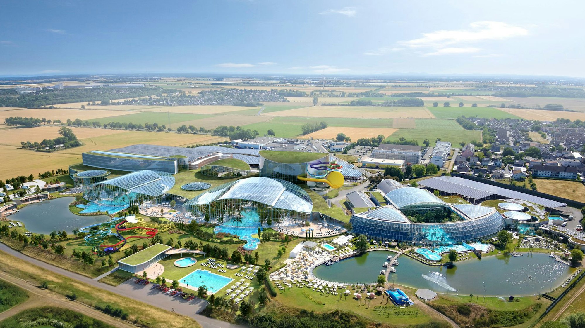 Das Bild zeigt die Anlage aus der Luft. Sie besteht aus mehreren verglasten Gebäuden, Grünflächen und Teichen.