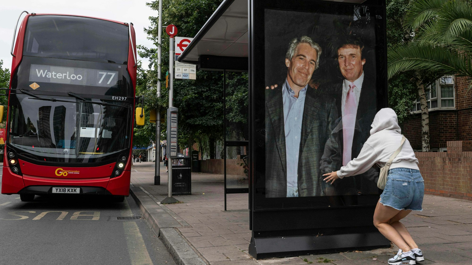 Aktivisten hängen ein Plakat, das US-Präsident Donald Trump und Jeffrey Epstein zeigt, an einer Bushaltestelle in der Nähe der US-Botschaft auf.