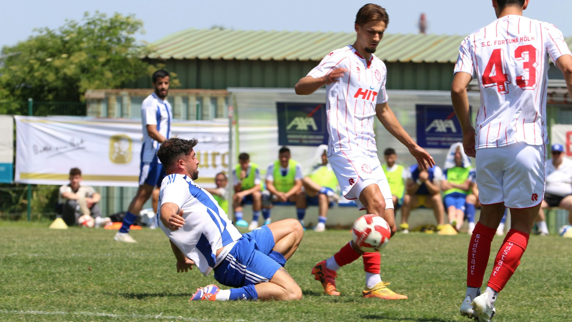 Der Spieler des SC Wißkirchen grätscht im Mittelfeld nach dem Ball, vor ihm zwei Spieler von Fortuna Köln.