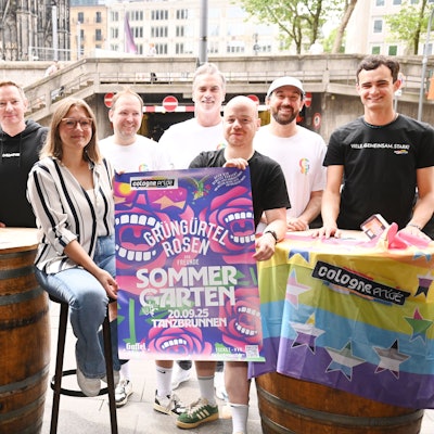 Mehrere Menschen stehen um ein Konzertplakat herum.