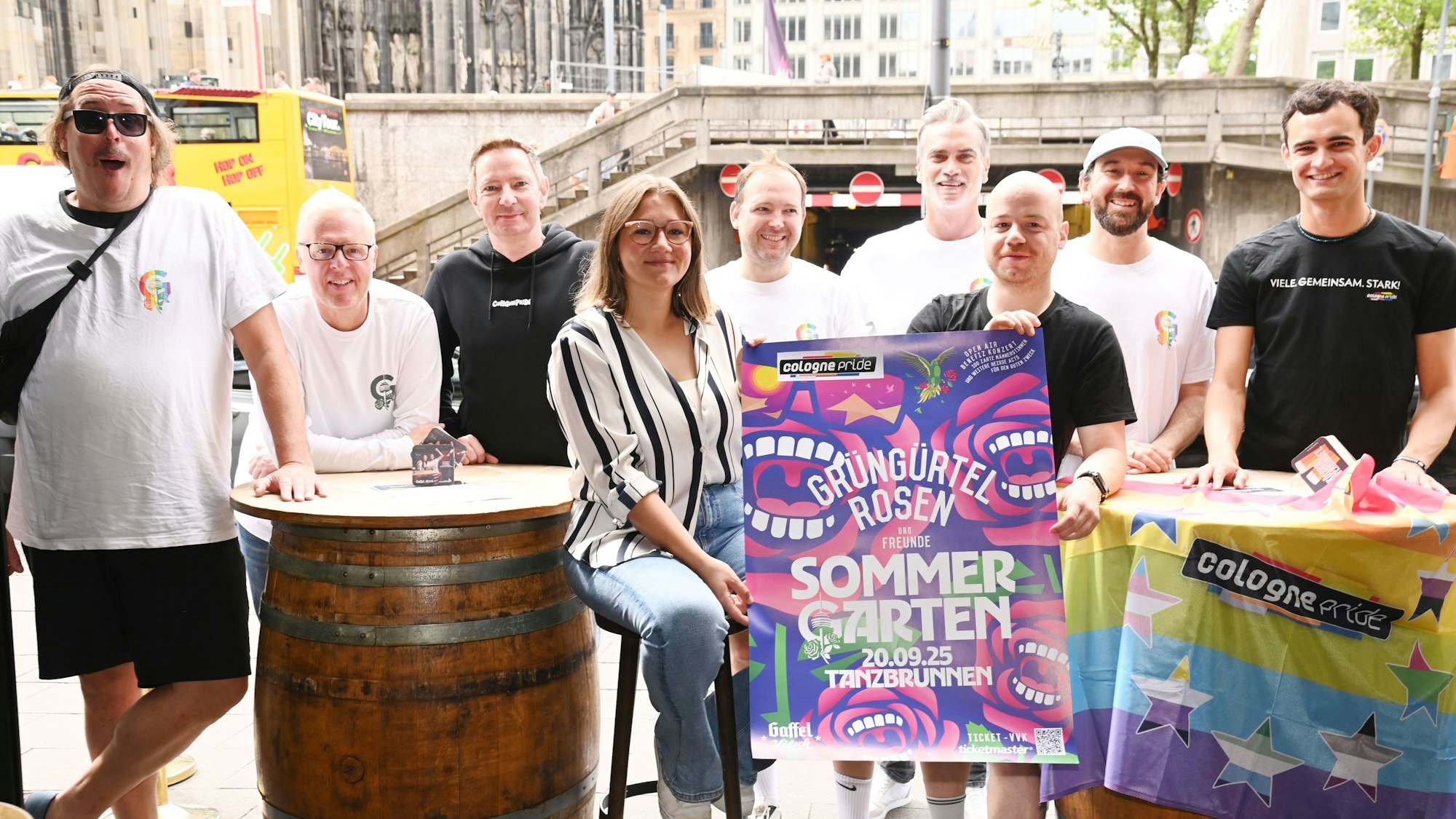 Mehrere Menschen stehen um ein Konzertplakat herum.