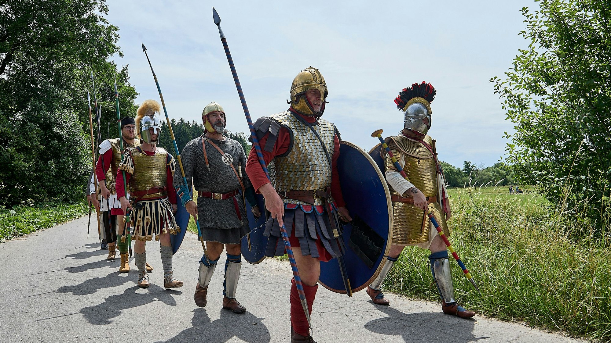 Als Römer verkleidete Männer gehen einen Weg entlang.
