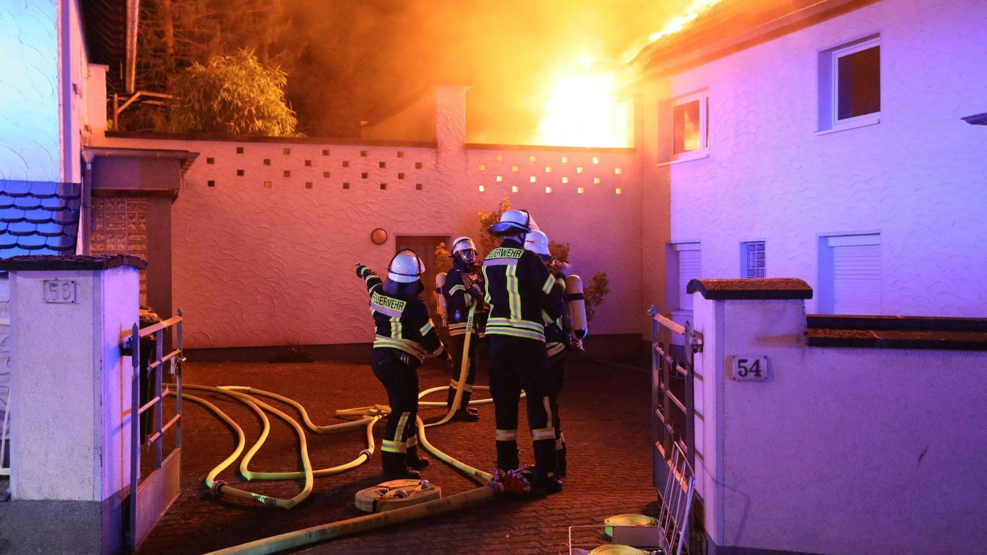 Feuerwehrleute löschen von einem Innenhof aus die Flammen.