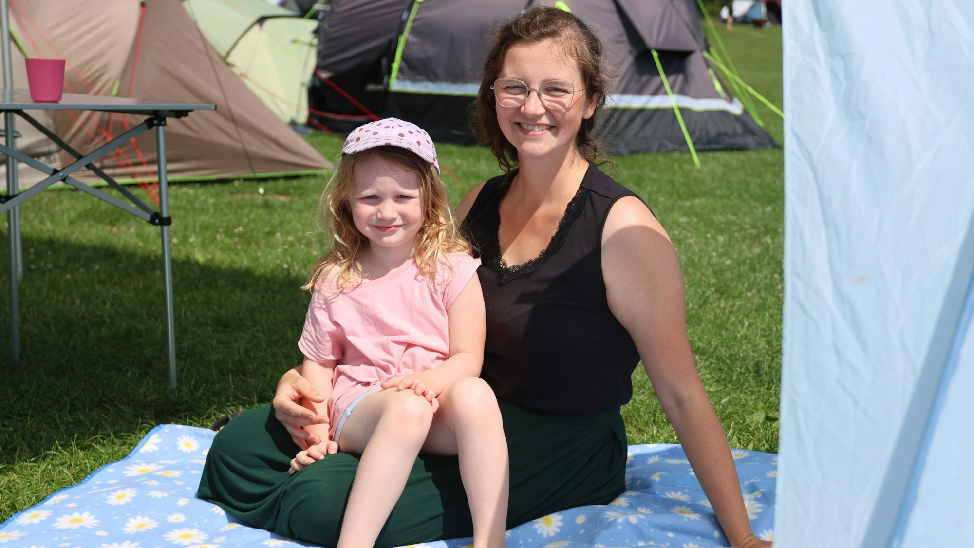 Eine Frau und ein Mädchen sitzen auf einer Decke.