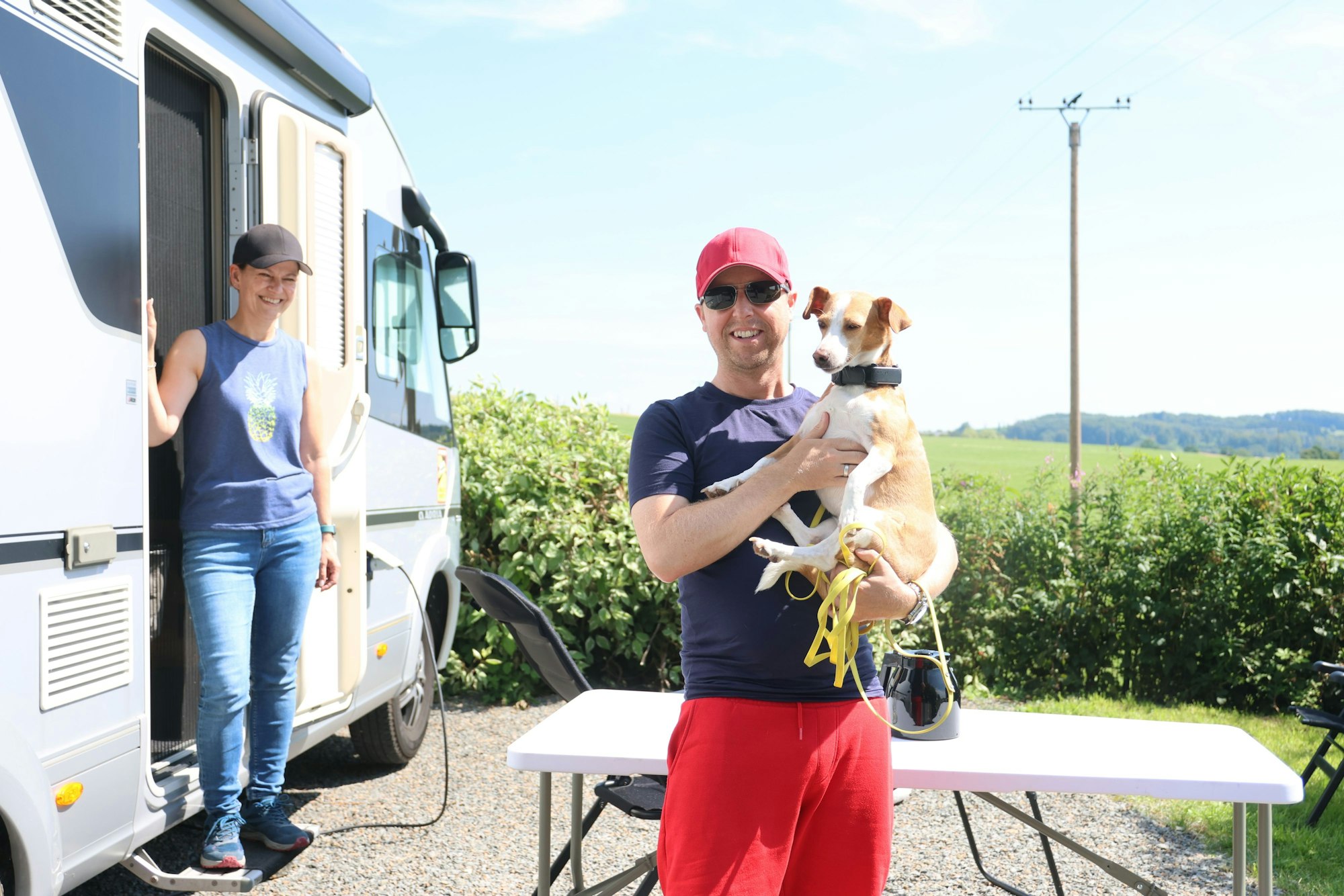 Ein Mann und eine Frau mit Hund vor einem Campingwagen.