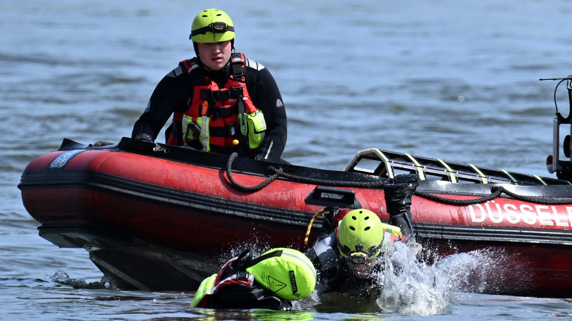 Ein Feuerwehrmann springt von einem Boot in den Rhein, um eine Übungspuppe zu "retten". (Archivbild)