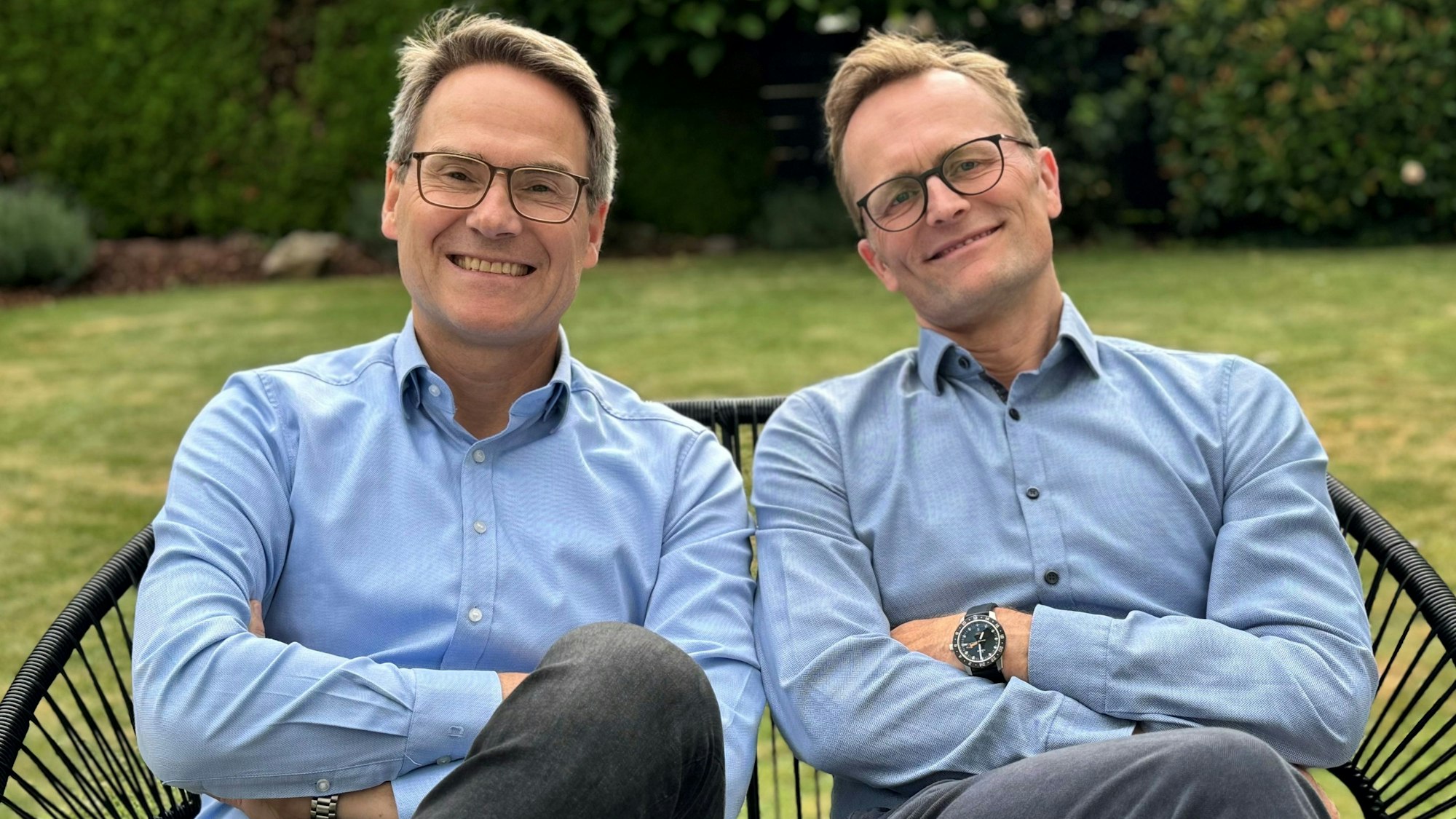 Zwei Männer, die Arme verschränkt, posieren für das Foto.