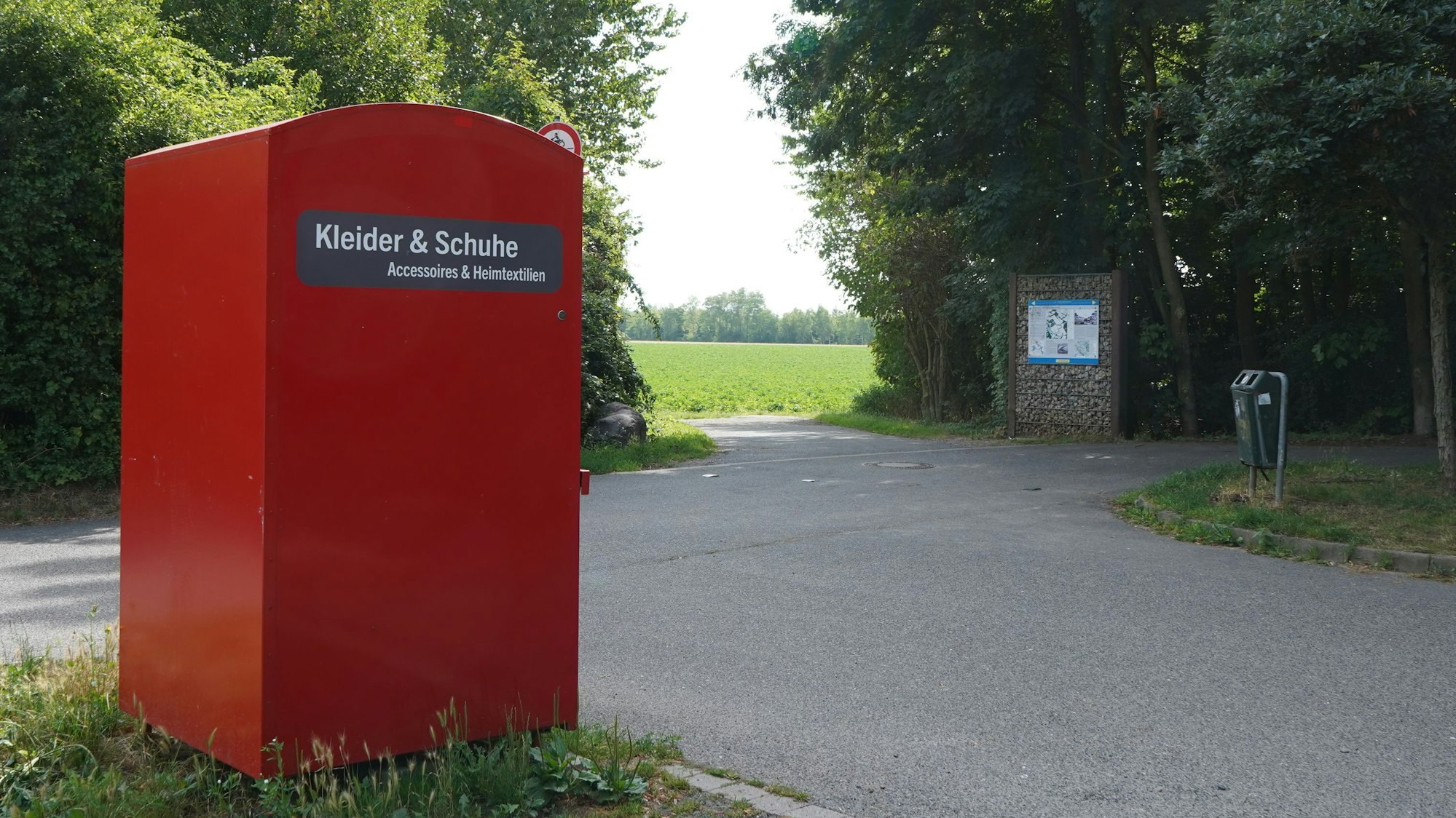 Das Foto zeigt einen Parkplatz, im Vordergrund eine Altkleidersammlung.