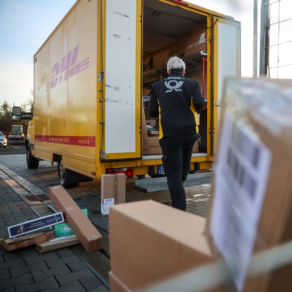Eine Mitarbeiterin der Deutsche Post DHL belädt ihr Fahrzeug mit Päckchen und Paketen. (Archivbild)