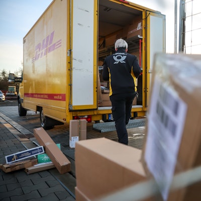 Eine Mitarbeiterin der Deutsche Post DHL belädt ihr Fahrzeug mit Päckchen und Paketen. (Archivbild)