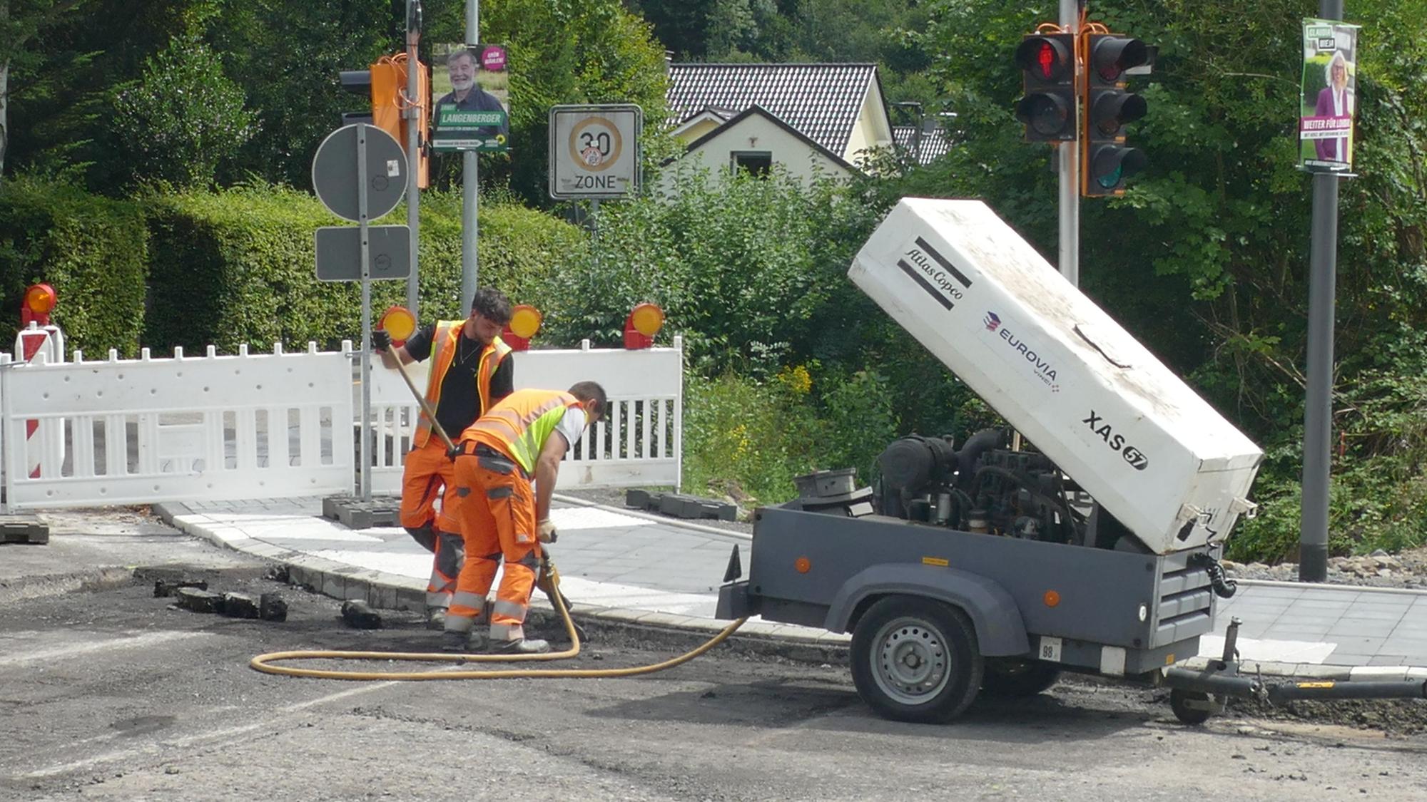 Zwei Männer arbeiten an einer Straßenbaustelle.