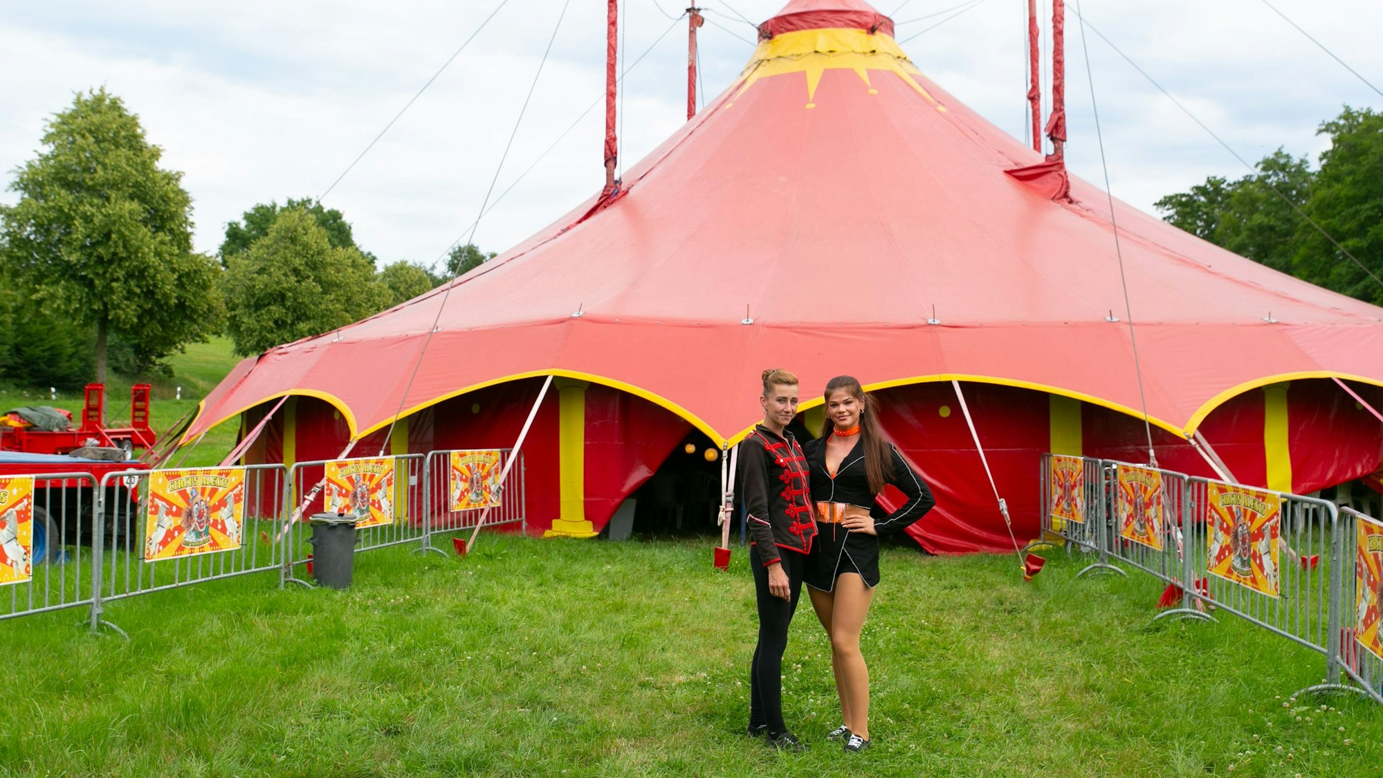 Zwei junge Frauen vor einem Zirkuszelt.