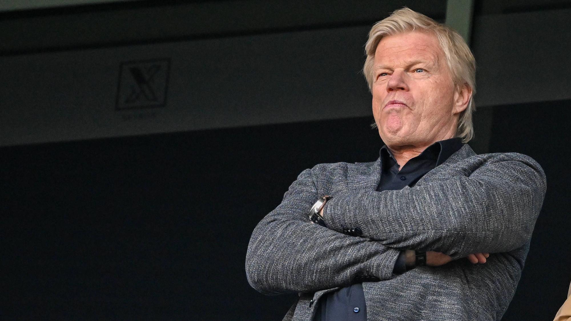 Oliver Kahn steht mit verschränkten Armen auf der Tribüne und guckt sich ein Spiel an.