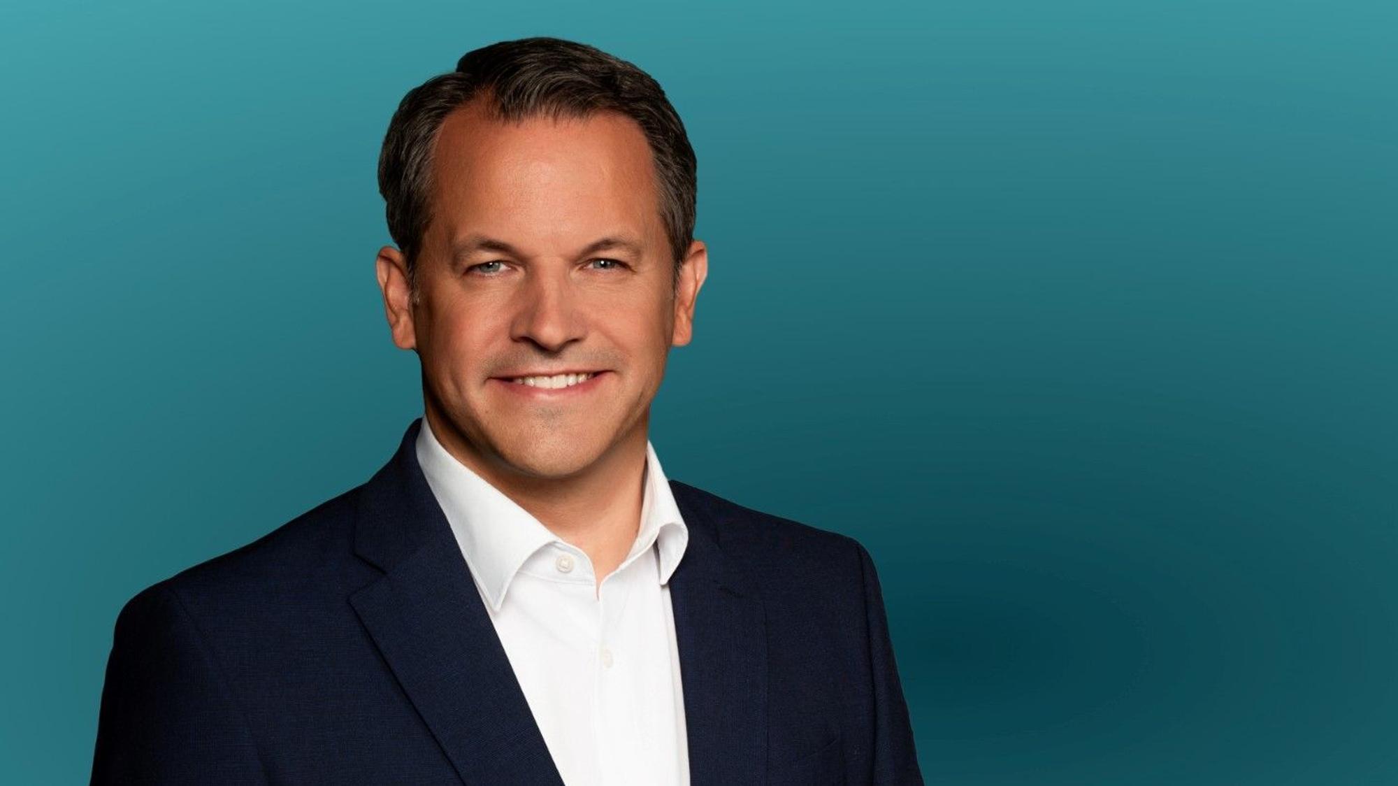 Ein Mann lächelt in die Kamera.