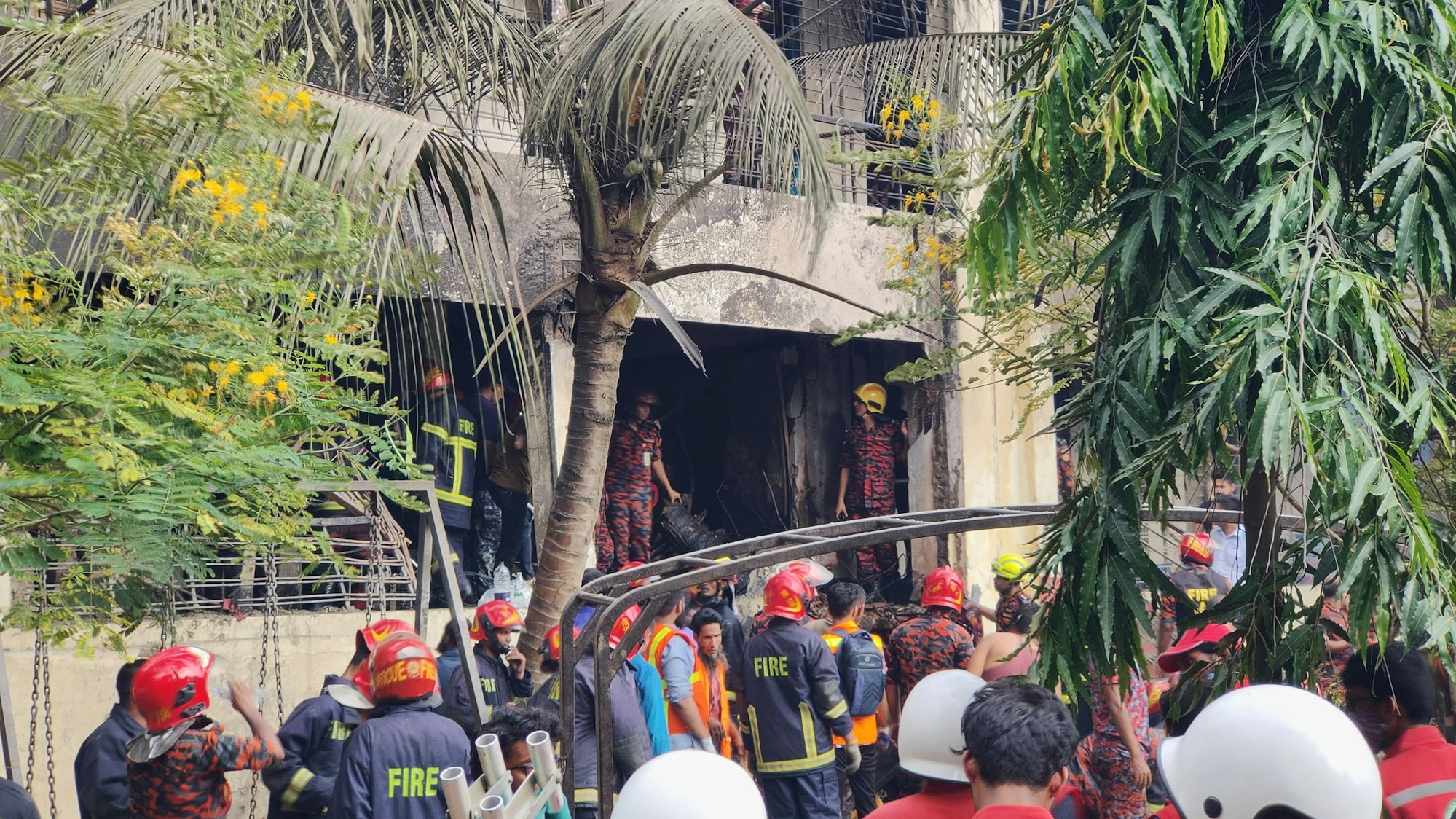 Feuerwehrleute untersuchen das Wrack eines Trainingsflugzeugs der Bangladesh Air Force, das auf ein Schulgelände abgestürzt ist.