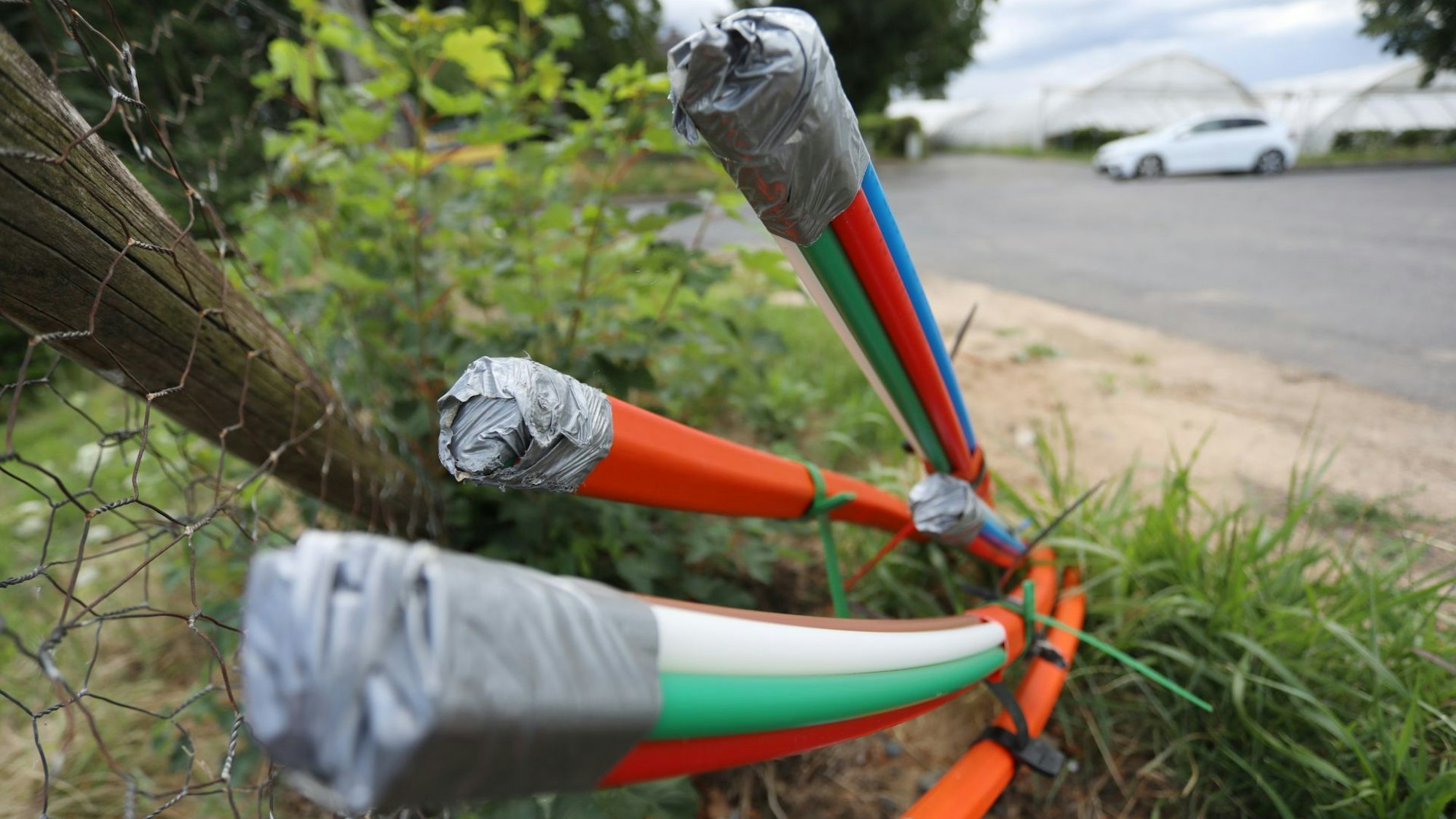 Mehrfarbige Kabel ragen aus dem Boden.