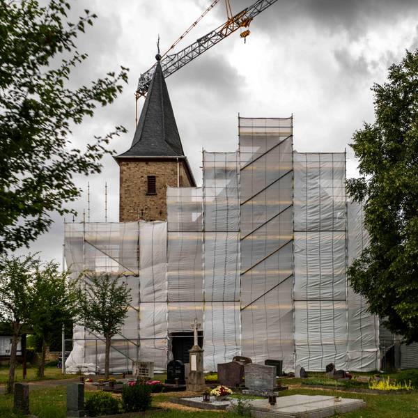 Die Kirche in Lövenich wird seit Jahren saniert. Das Haupthaus ist eingerüstet und mit Planen verhängt.
