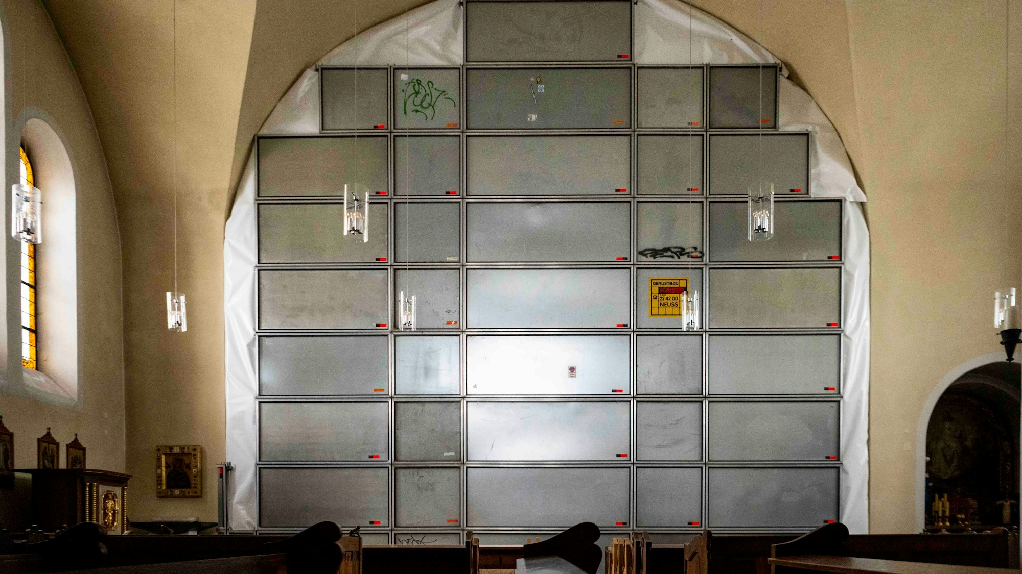 Im Innenraum der Pfarrkirche wird eine Wand mit Metallplatten und Folie geschützt.