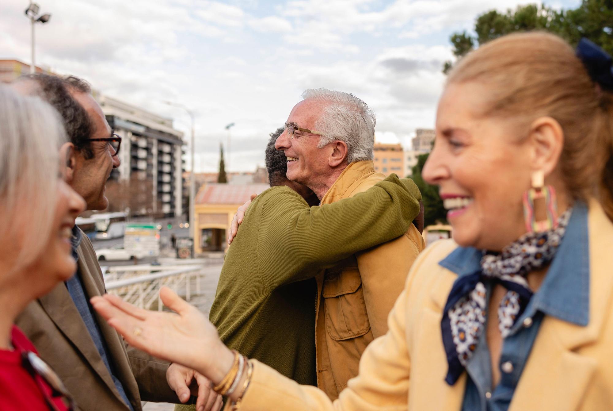 Senior friends socializing and hugging outdoors in an urban setting model released, Symbolfoto, JCCMF12883