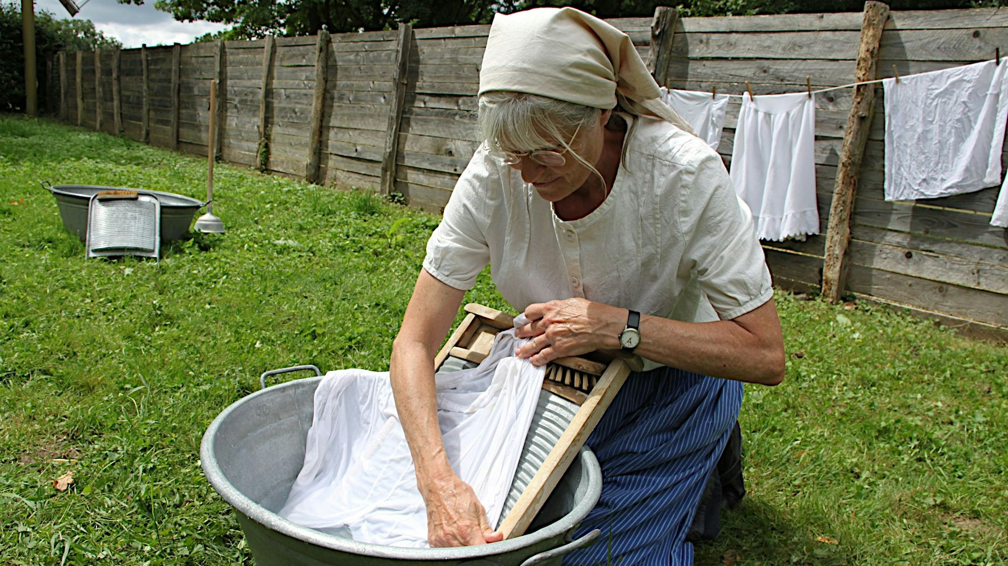 Andrea Rolfes-Koenen schrubbt Wäsche in einer Zinkbütte.