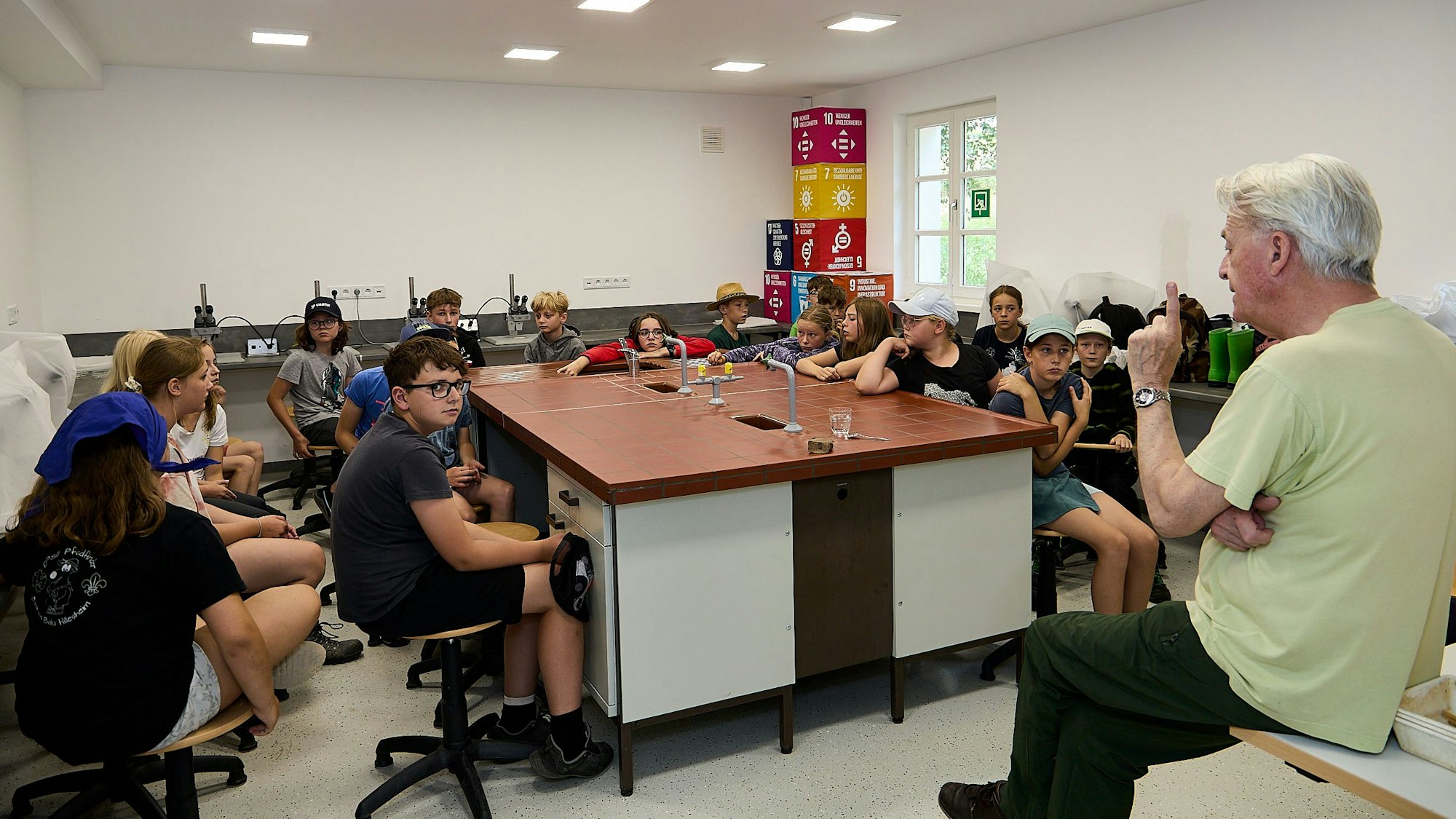 Jörg Müller sitzt vor einer Gruppe Kinder und spricht zu ihnen.