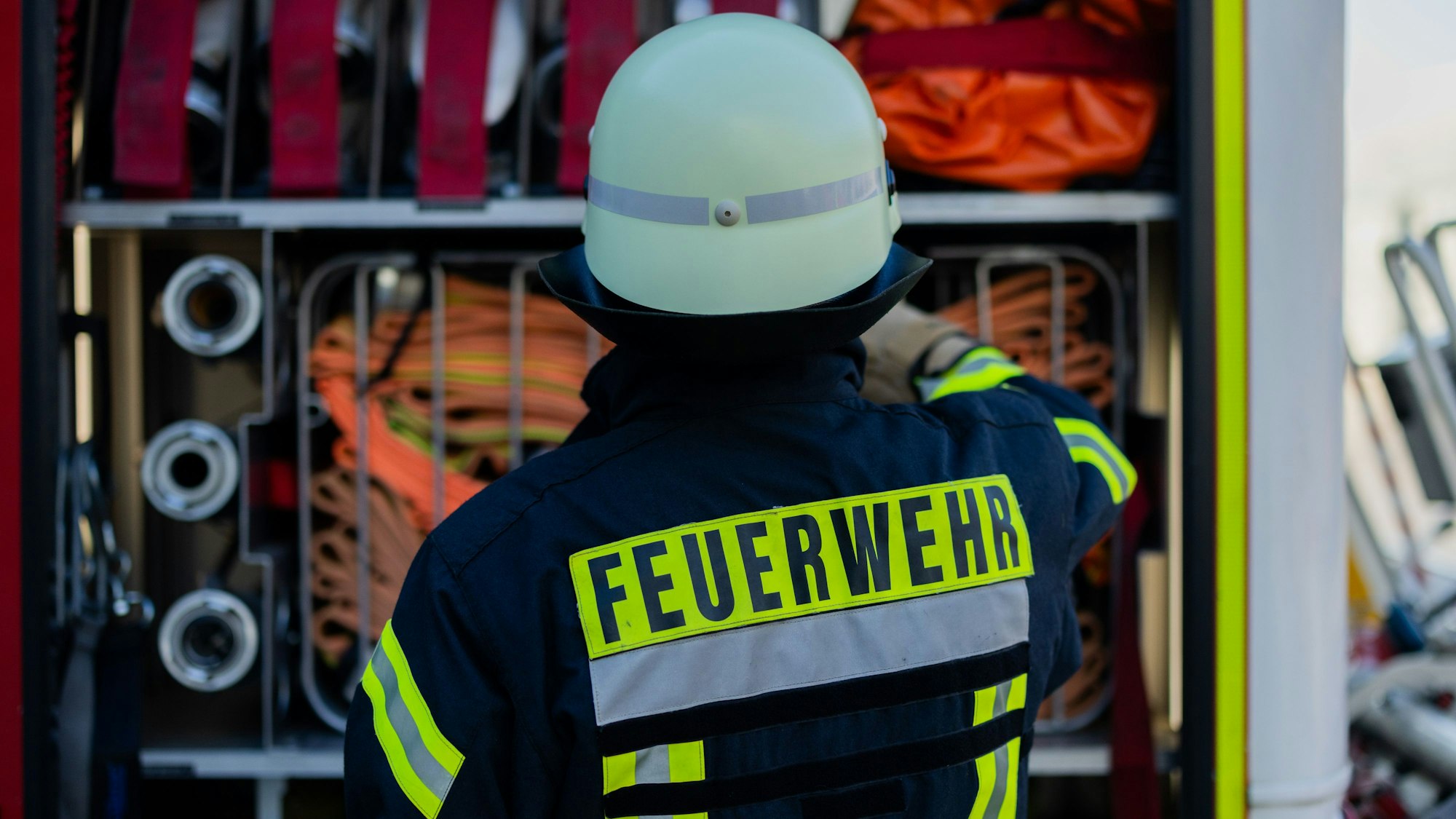 Ein Feuerwehrmann holt Ausrüstung aus einem Einsatzfahrzeug.