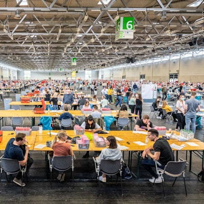 Eine Halle ist voller Wahlhelfer und Wahlhelferinnen, die Stimmzettel auszählen.