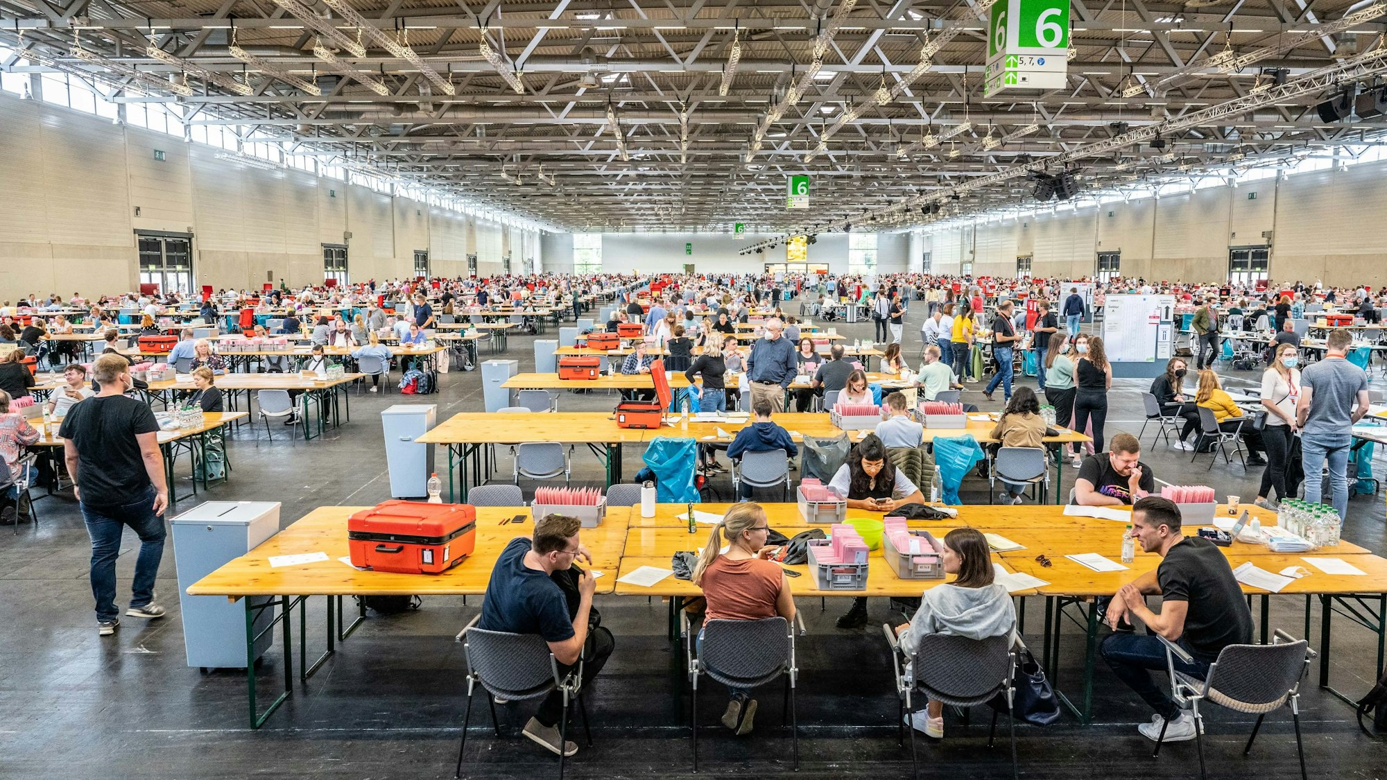 Eine Halle ist voller Wahlhelfer und Wahlhelferinnen, die Stimmzettel auszählen.