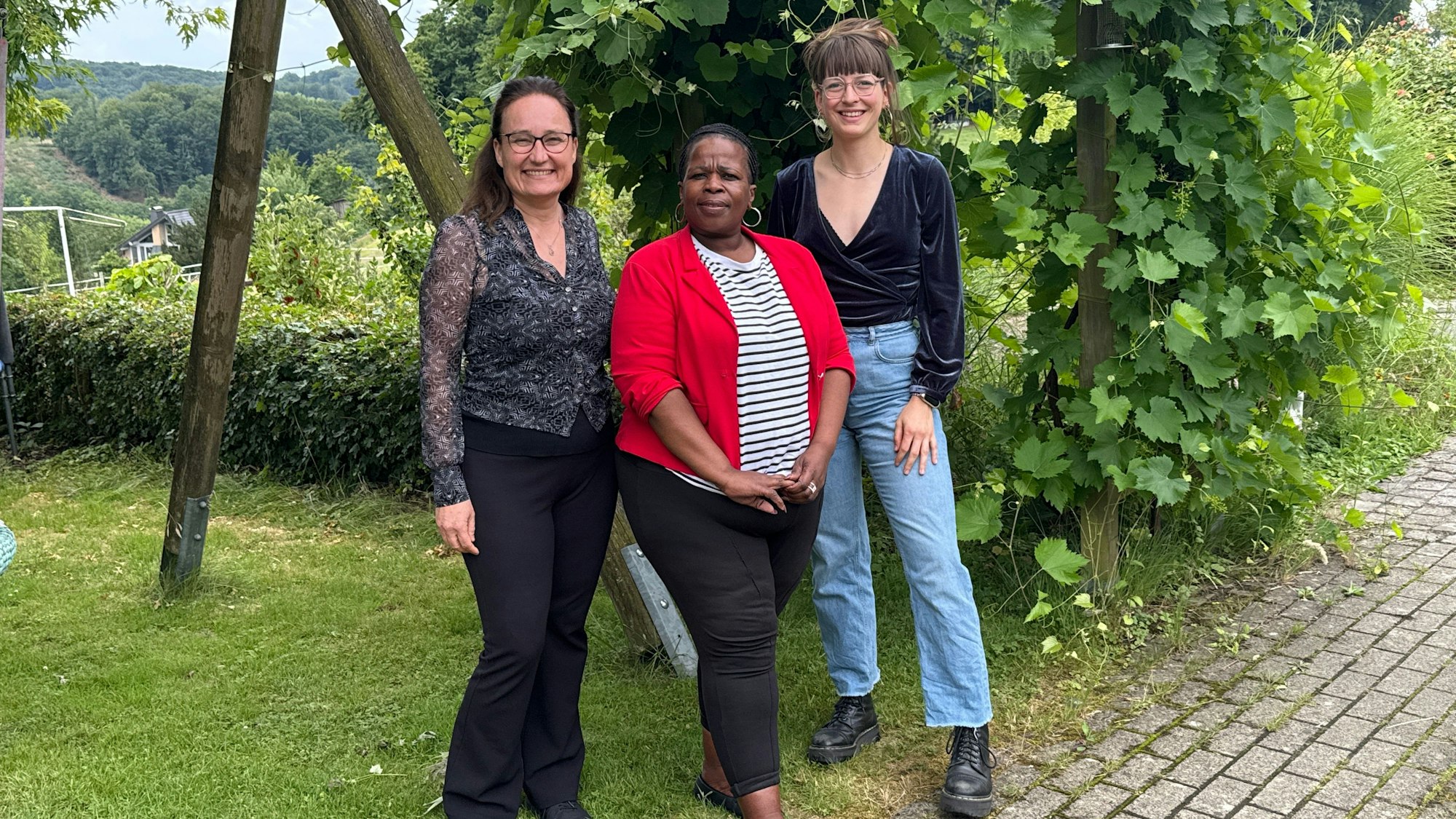 Drei Frauen lächeln in die Kamera.