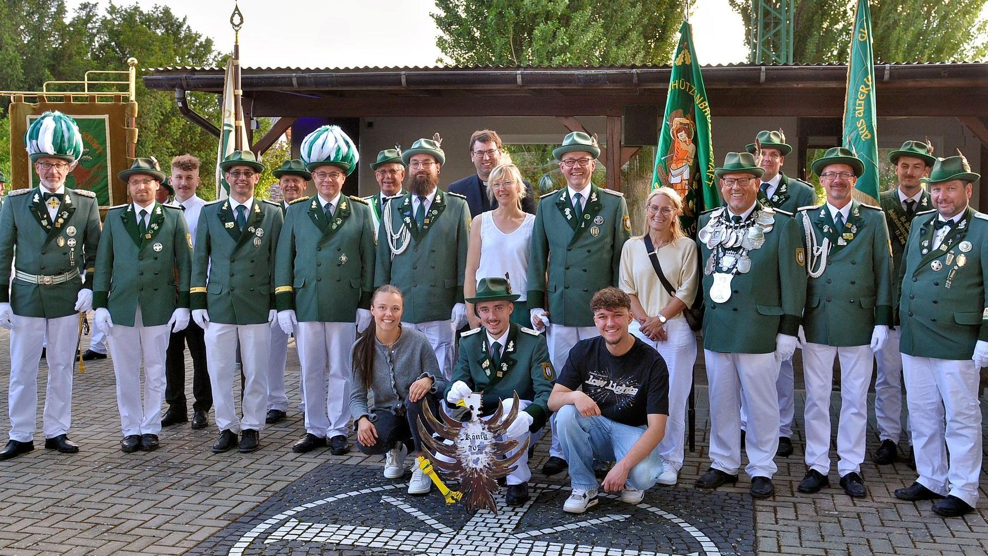 Eine Gruppe Männer steht in grün-weißer Schützen-Uniform und mit ein paar Frauen in ziviler Kleidung auf einem Platz.