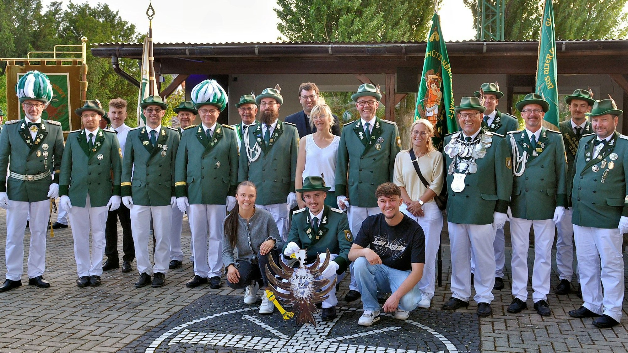 Eine Gruppe Männer steht in grün-weißer Schützen-Uniform und mit ein paar Frauen in ziviler Kleidung auf einem Platz.