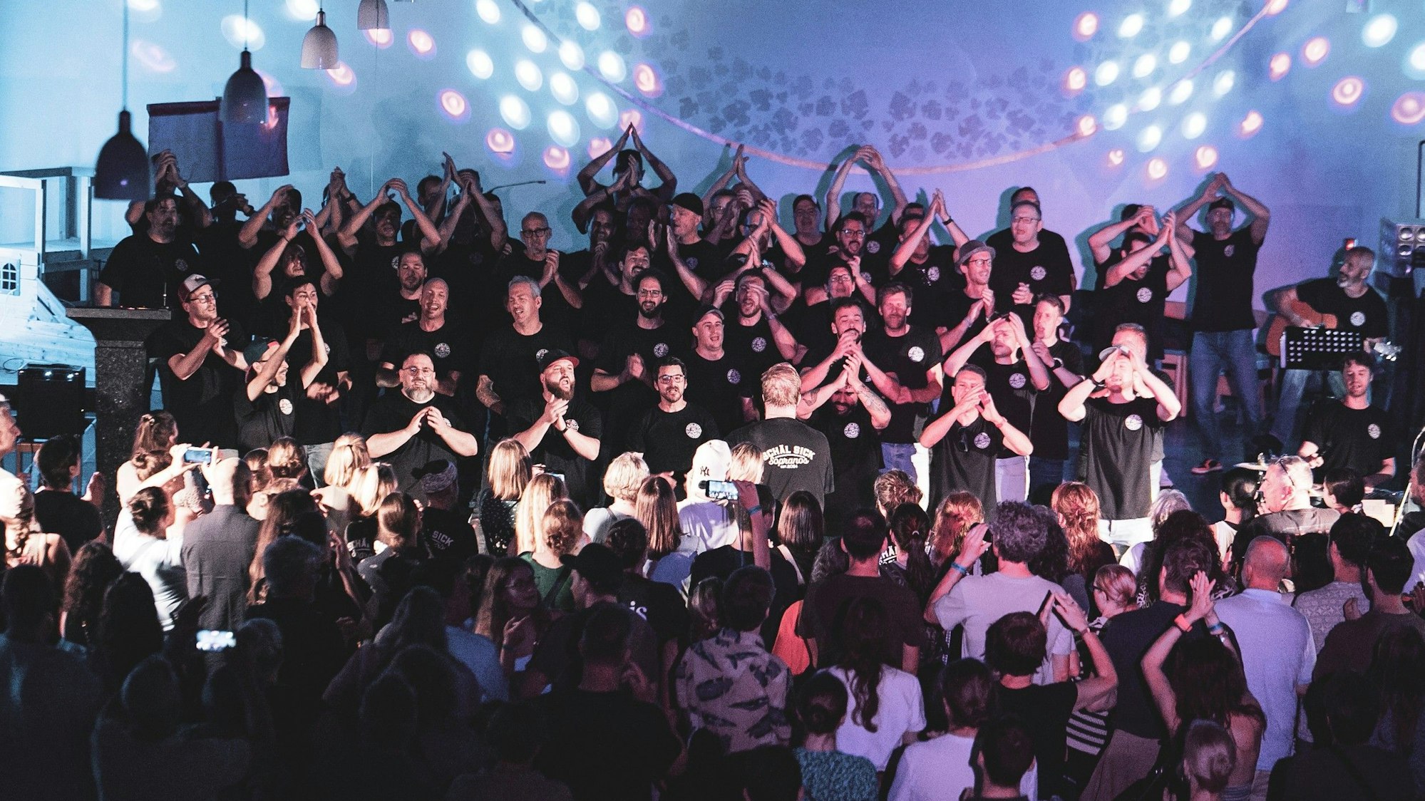 Der Männerchor Schäl Sick Sopranos performt bei einem Konzert vor einem Publikum.