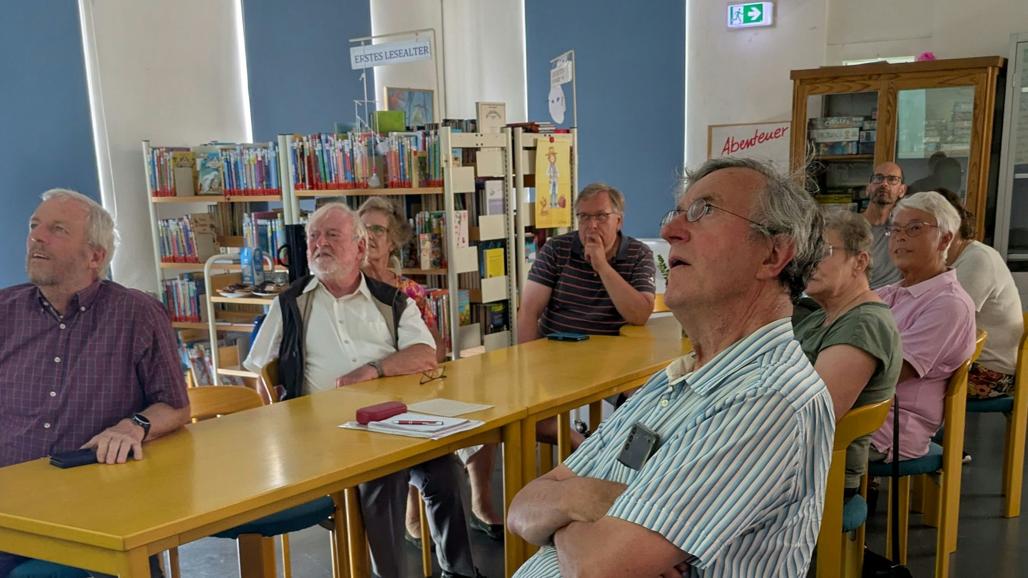 Eine Gruppe von Menschen sitzt an einem Tisch und blickt in eine Richtung.