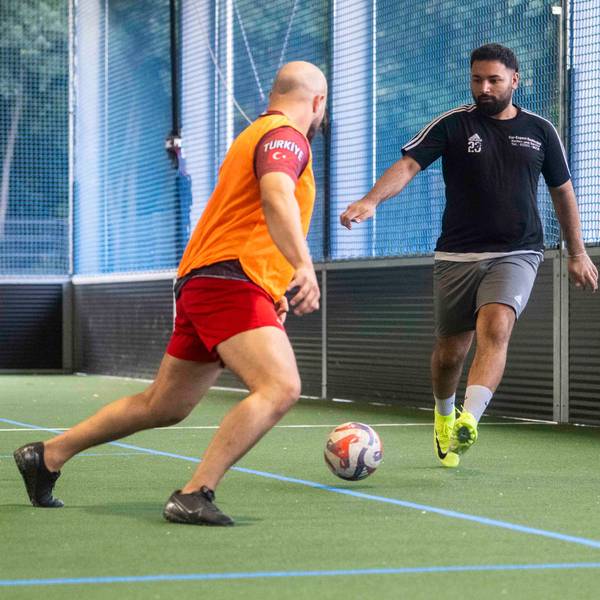 Spieler des Euskirchener TSC trainieren in einer Sporthalle das Fußballspielen. Einige tragen orangefarbene Leibchen.