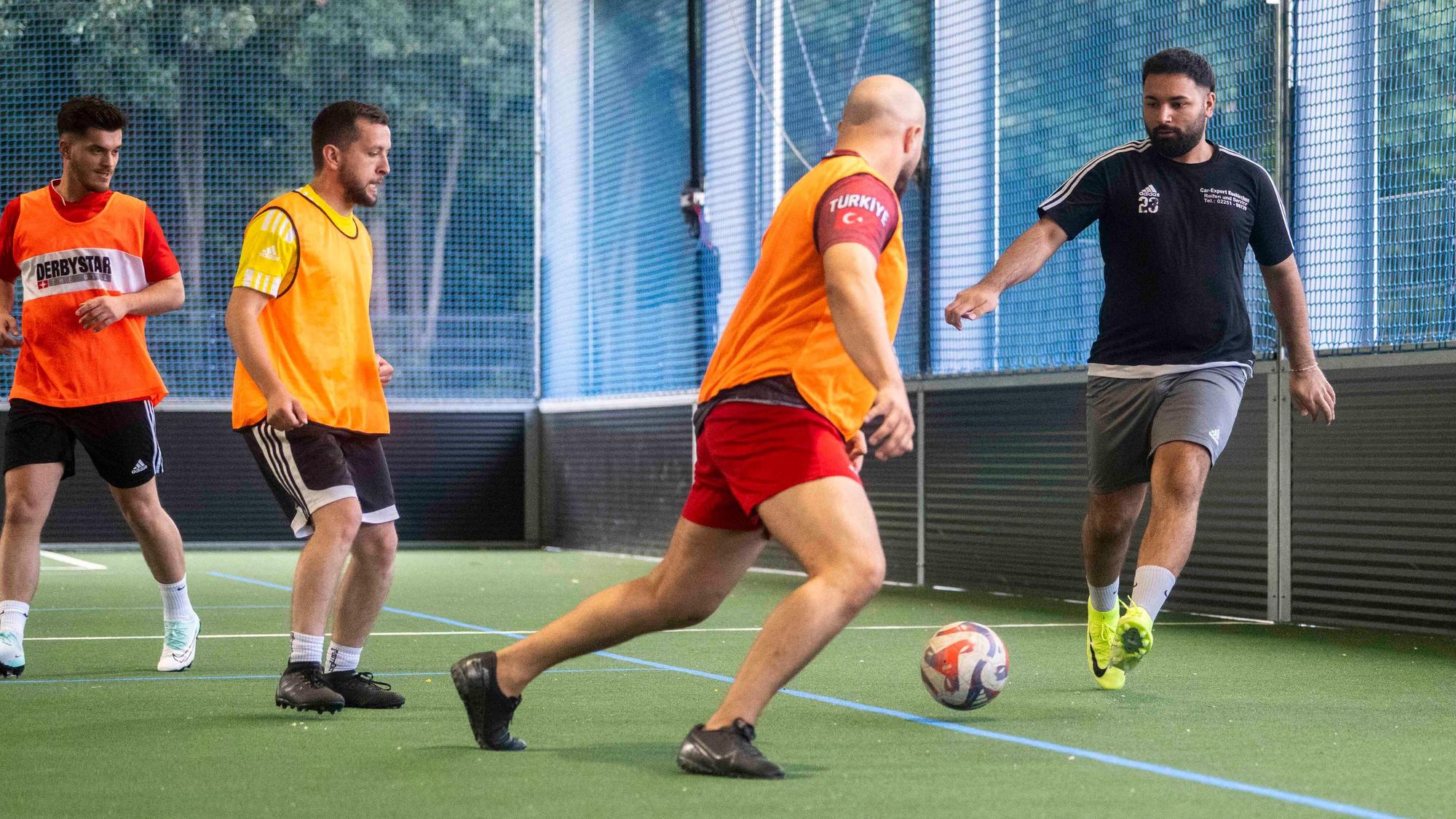 Spieler des Euskirchener TSC trainieren in einer Sporthalle das Fußballspielen. Einige tragen orangefarbene Leibchen.