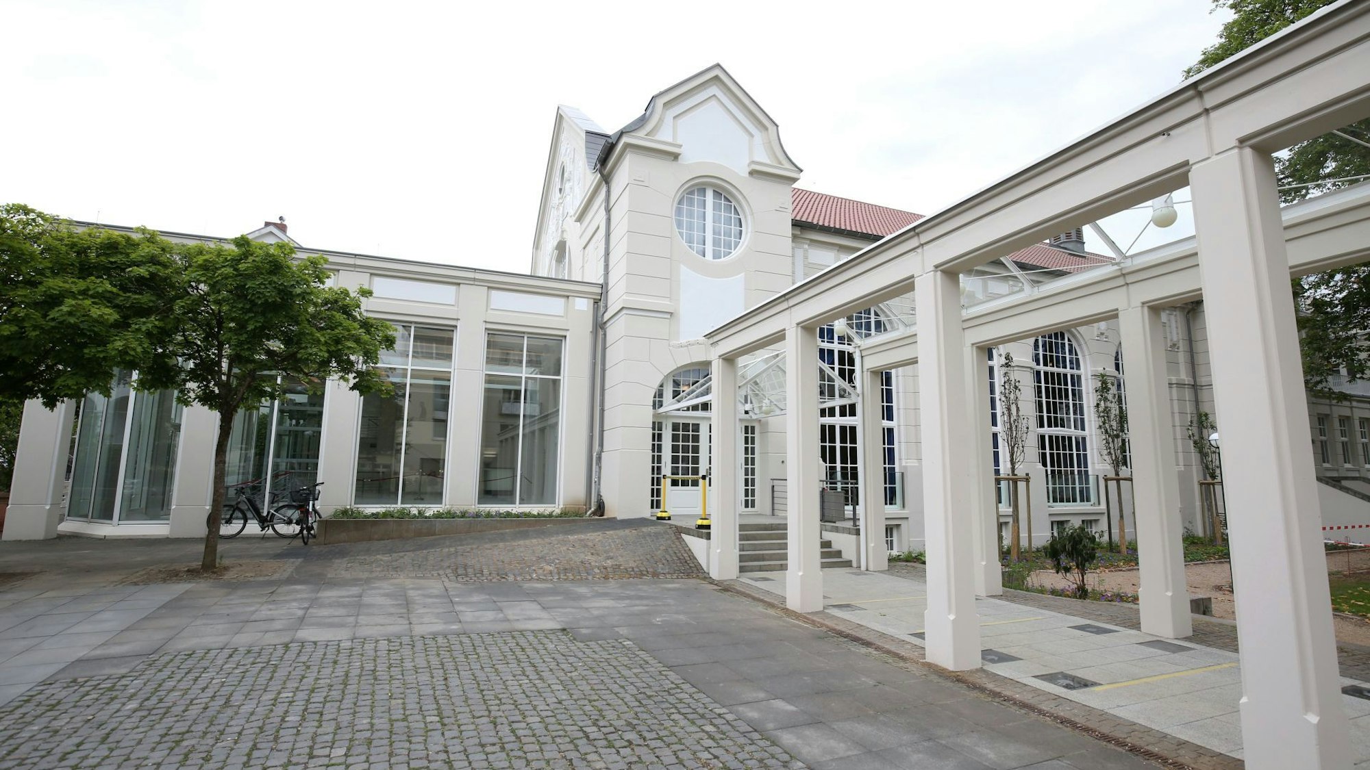 Ein historisches Gebäude mit angebautem Foyer und einem Arkadengang.