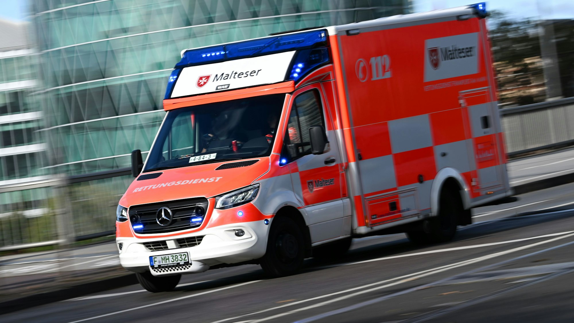 Ein Rettungswagen des Malteser Hilfsdienstes ist mit eingeschaltetem Blaulicht auf dem Weg zum Universitätsklinikum