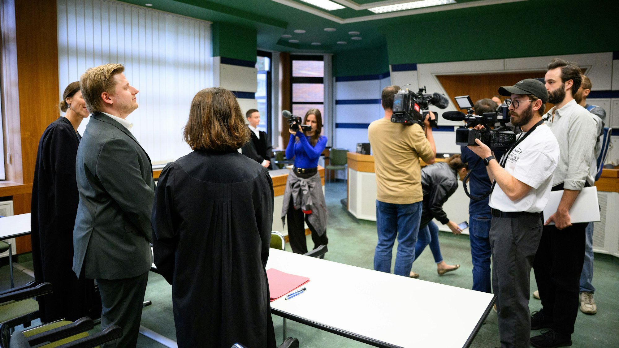 El Hotzo (2.v.l) steht zusammen mit seinen Rechtsanwältinnen Kerstin Schmitt und Carolin Lütcke (l) zu Beginn vom Prozess gegen ihn im Gerichtssaal.
