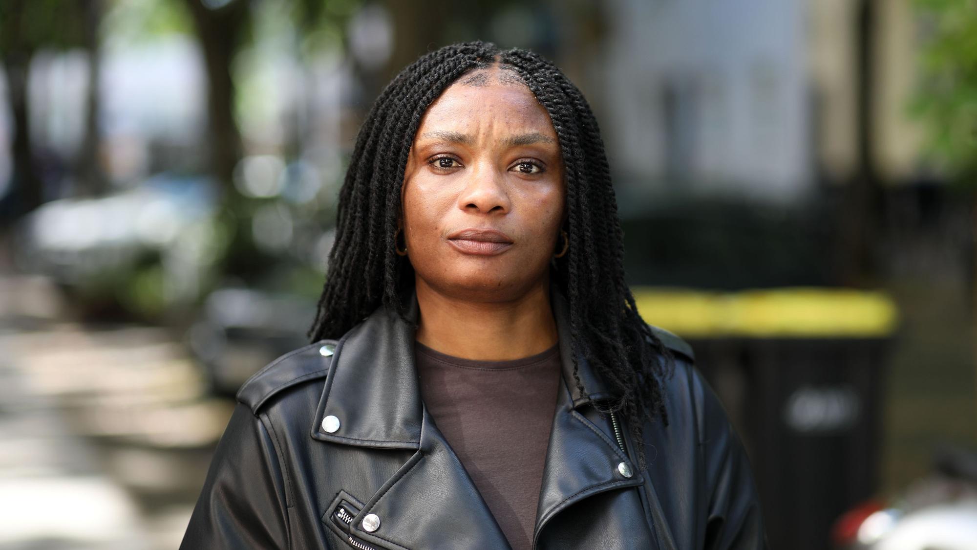 Janefrancis Kalu aus Nigeria im Porträt. Sie trägt ihre schwarzen Haare lang und eine schwarze Lederjacke mit braunem T-Shirt.