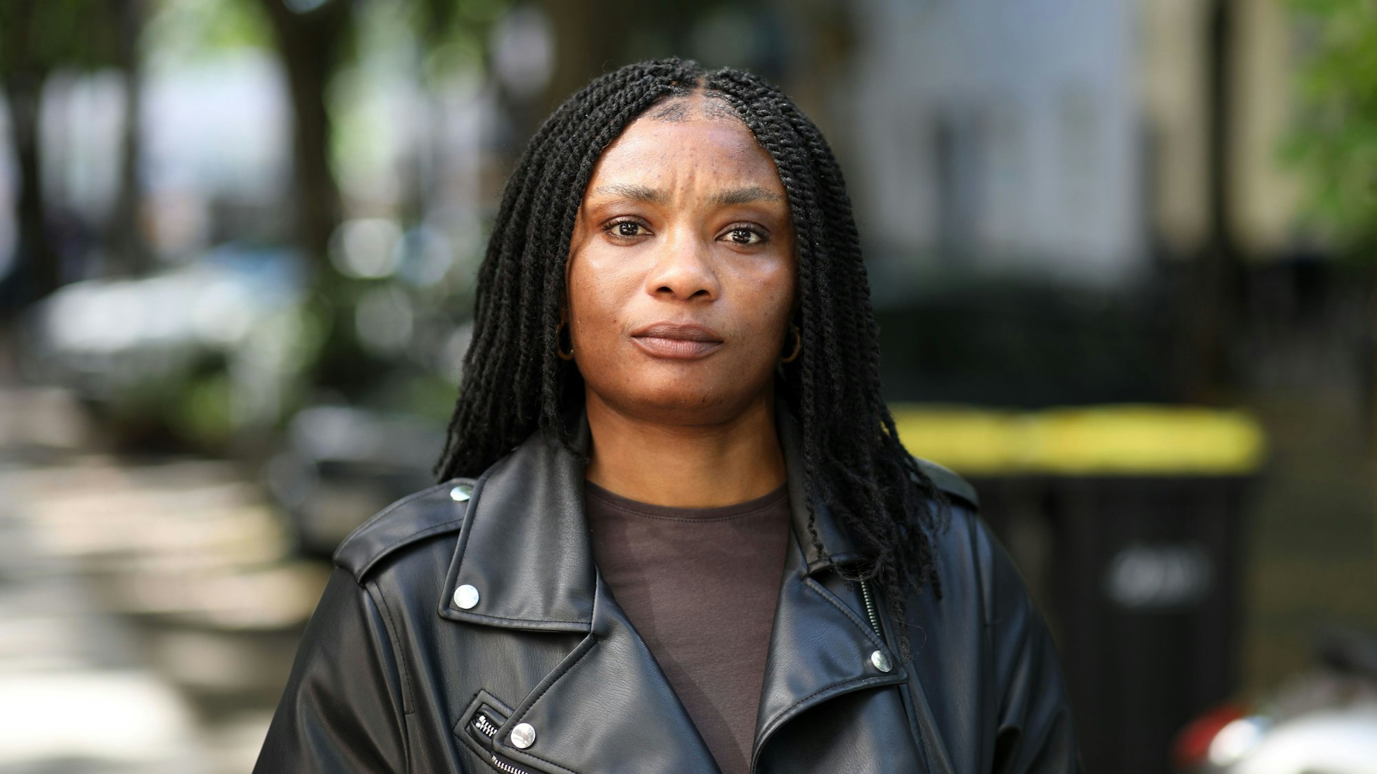 Janefrancis Kalu aus Nigeria im Porträt. Sie trägt ihre schwarzen Haare lang und eine schwarze Lederjacke mit braunem T-Shirt.