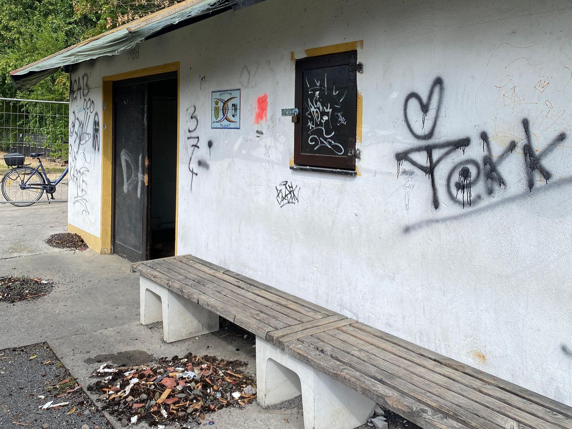 Auf der Fassade des Vereinshauses sind unschöne Schmierereien. Auf dem Boden davor liegen Müll und Dreck.