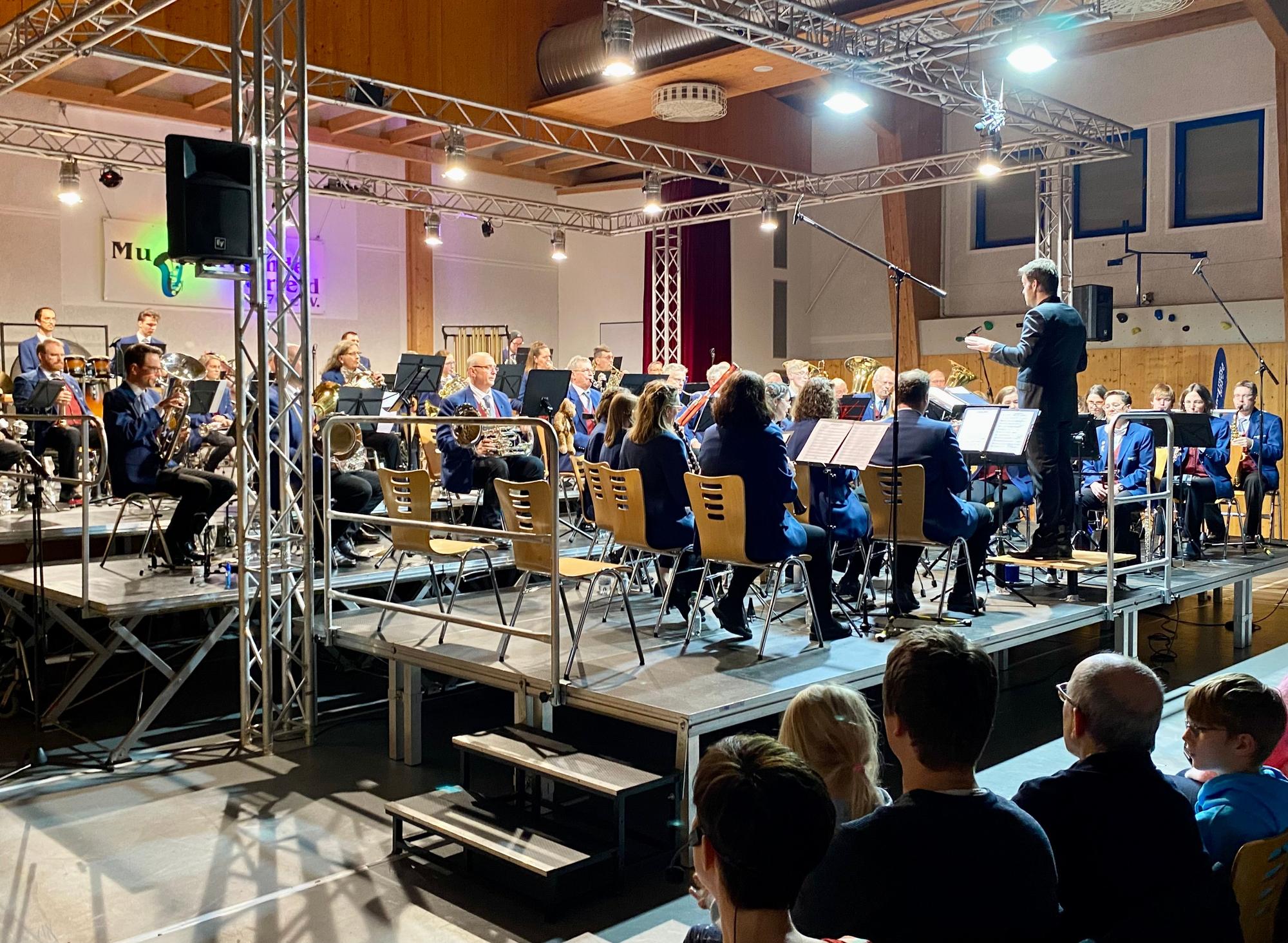 Auf dem Bild ist ein Orchester auf einer Bühne zu sehen.