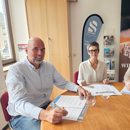 Hubert Schmidt, Bianka Renn und Petra Schumacher-Hendus sitzen an einem Tisch und haben Unterlagen vor sich liegen.